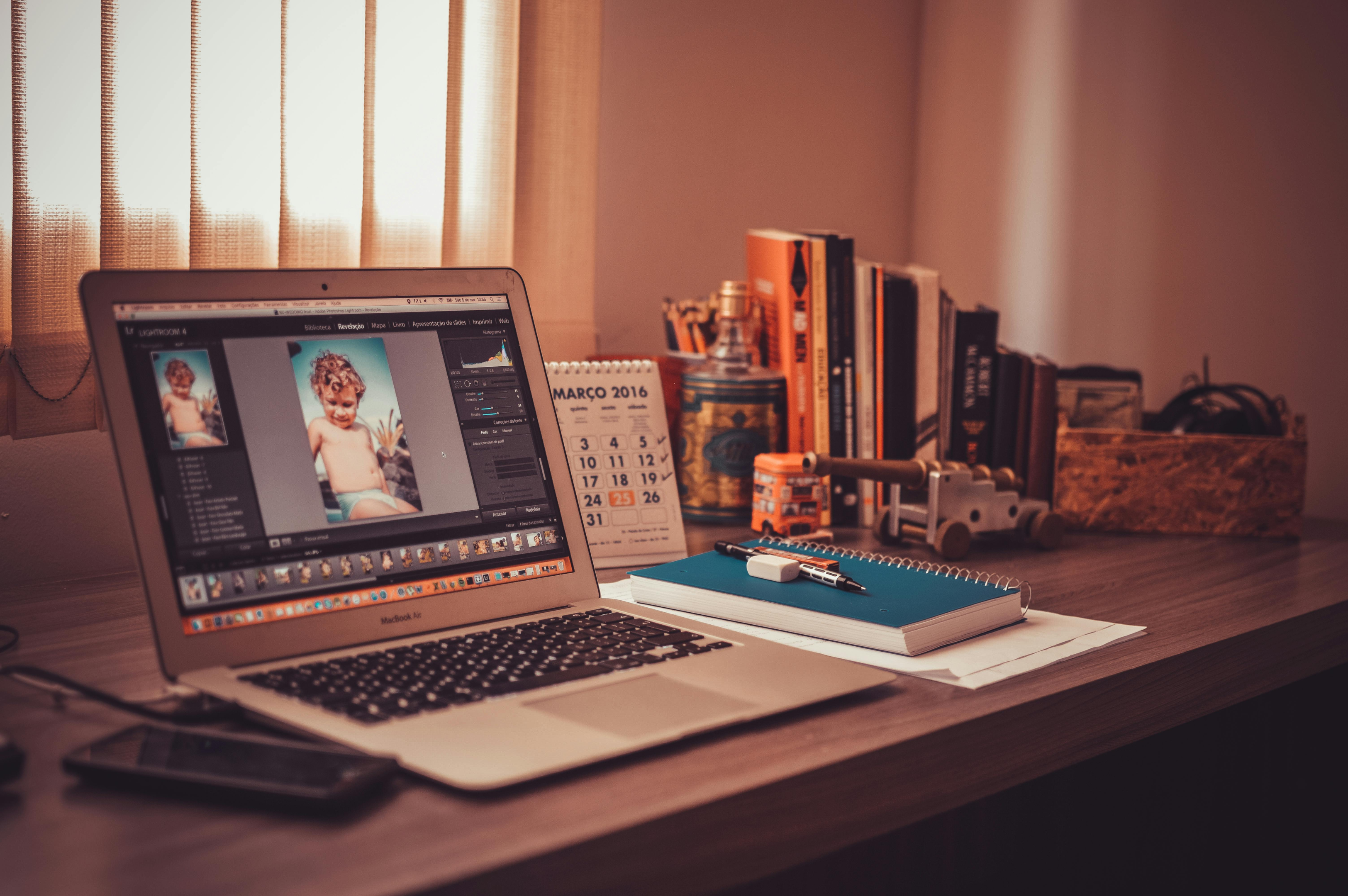 Laptop open on desk with photo editing software on-screen