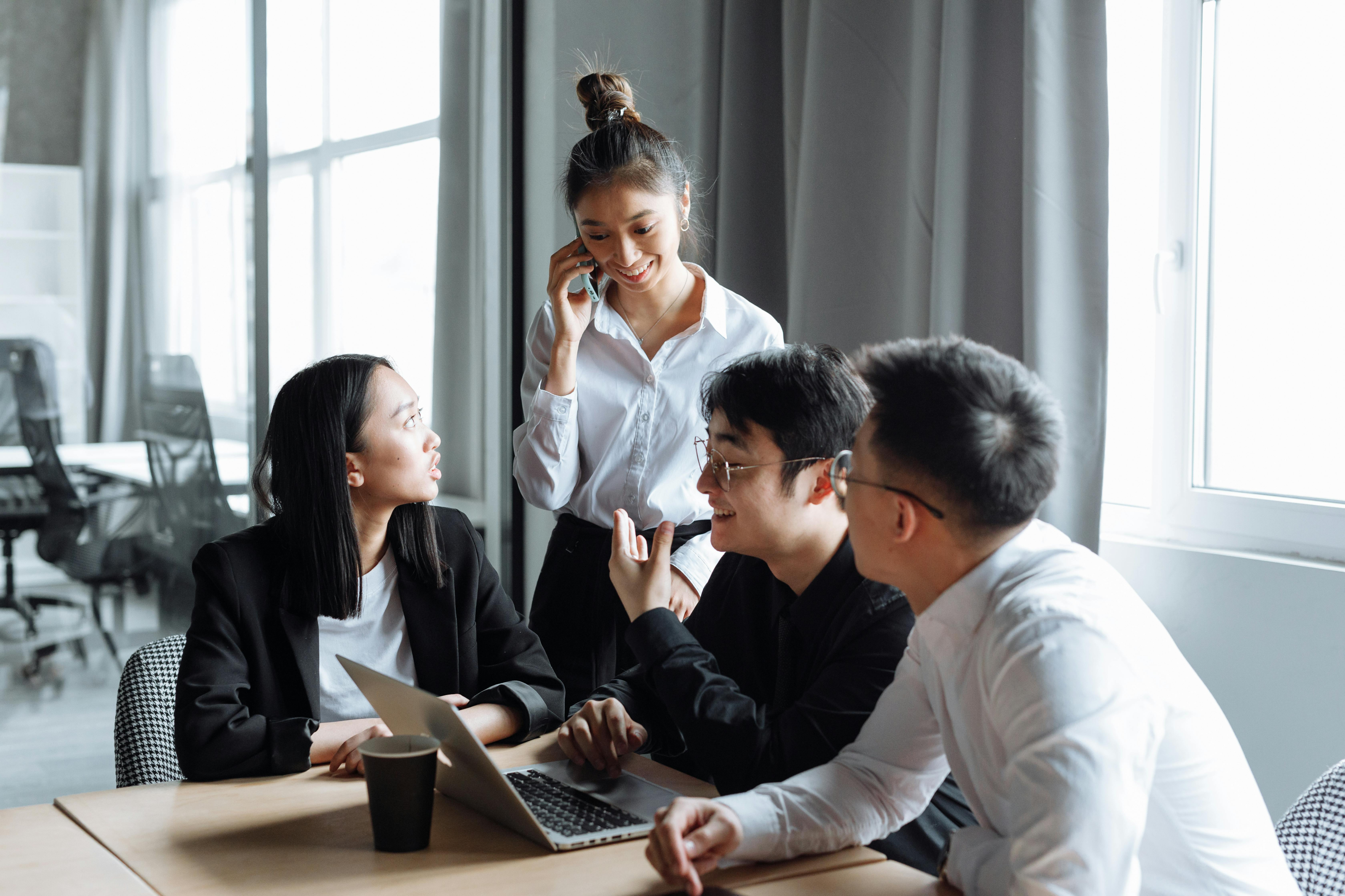 Office colleages collaborating around laptop