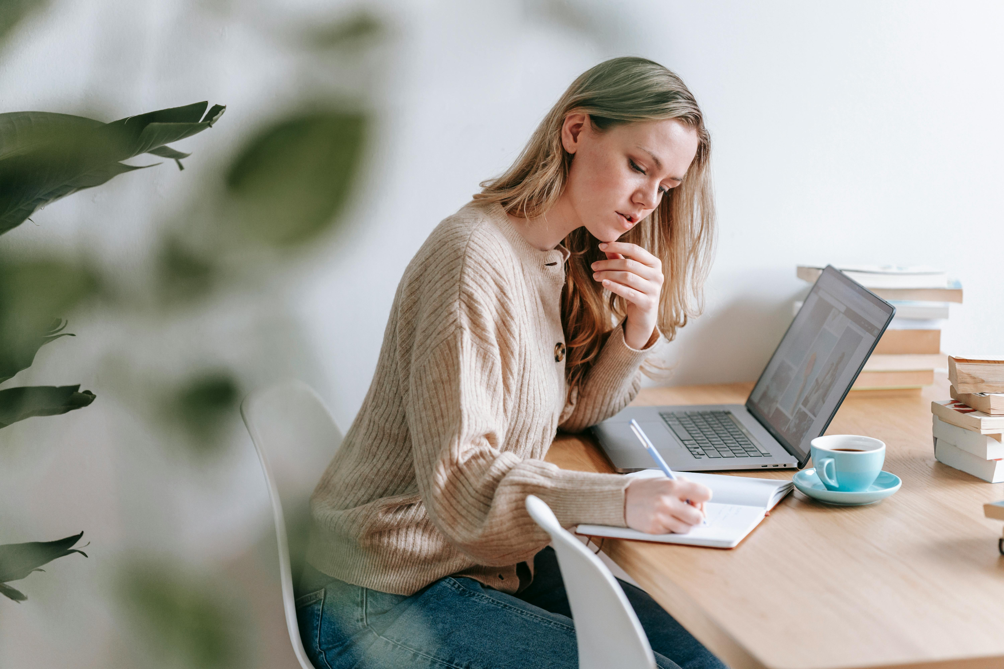 Woman sitting at table working remotely on laptop