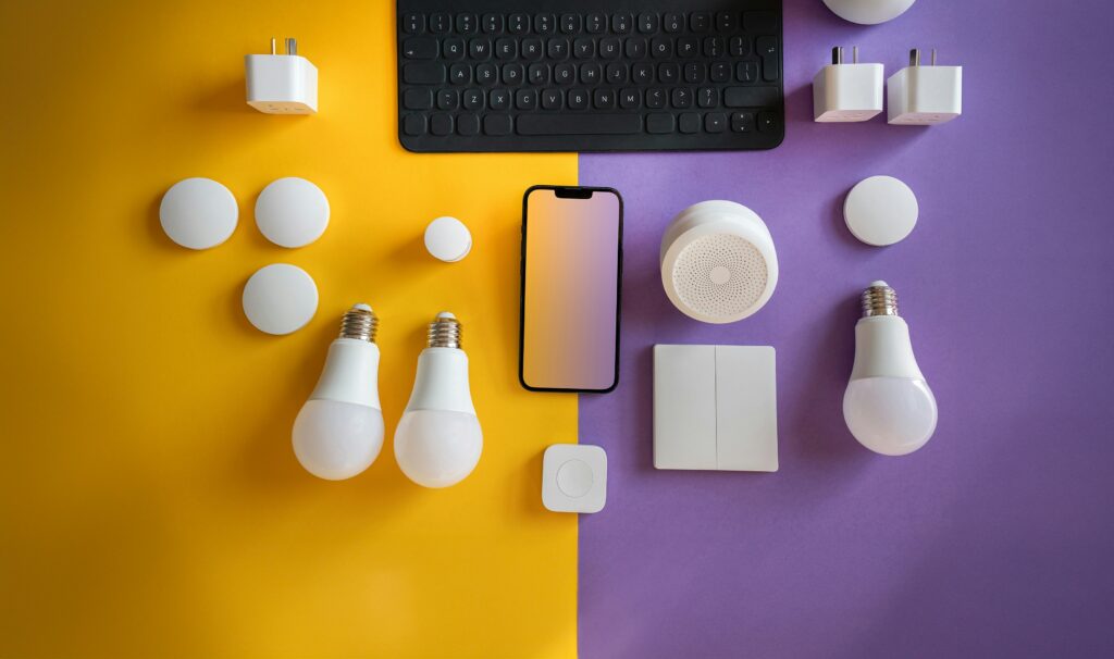 Various smart lighting and power devices with a smartphone and keyboard on a yellow and purple background