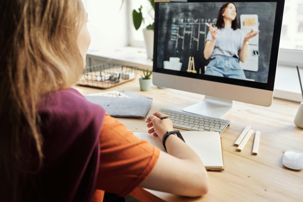 A woman watching an online class on an iMac