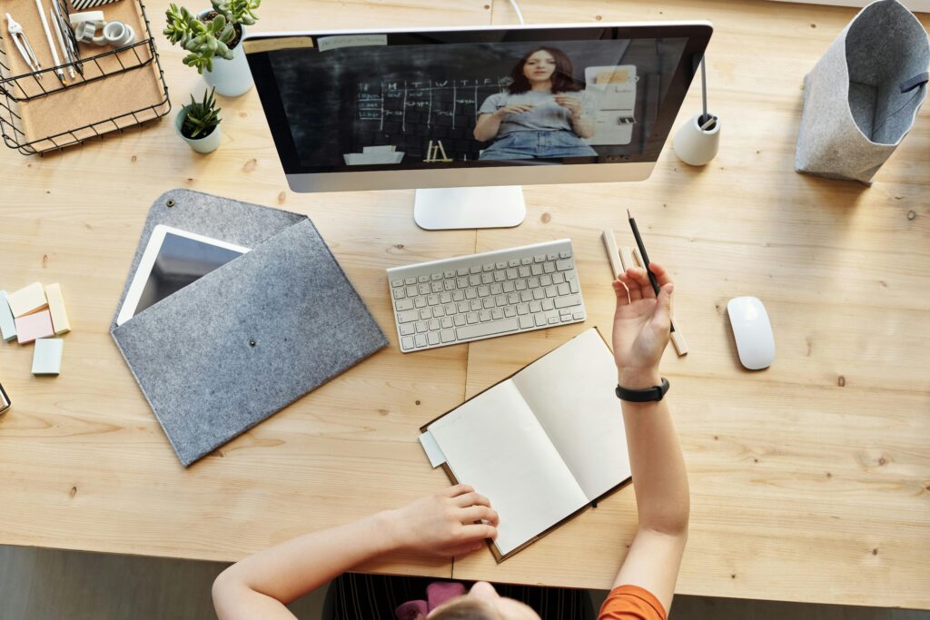 Top-down view of a girl watching an e-learning video on an iMac
