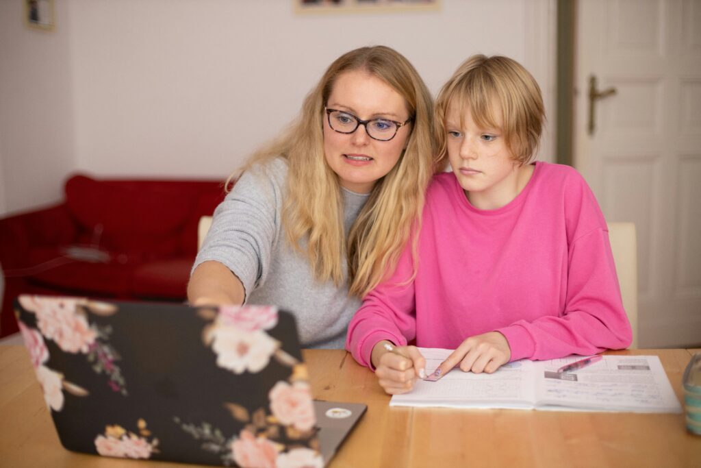 Mother helping daughter with online learning on a laptop