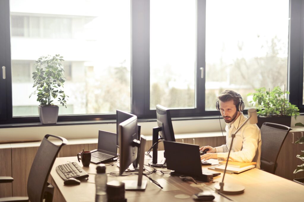 man working on a desk with multiple computers in an office setting.