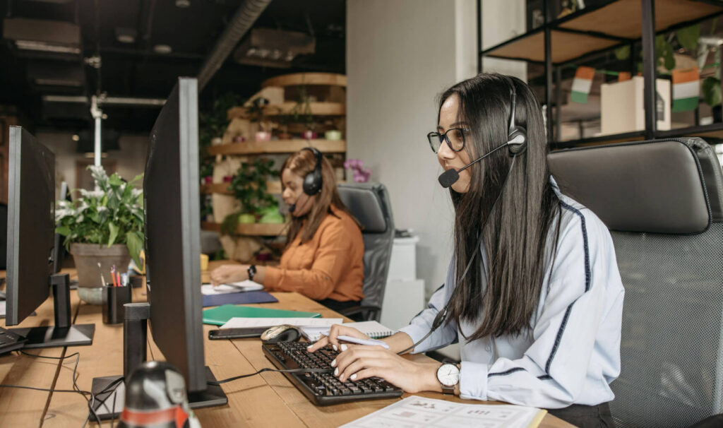 Two tech support team members taking calls and using PCs