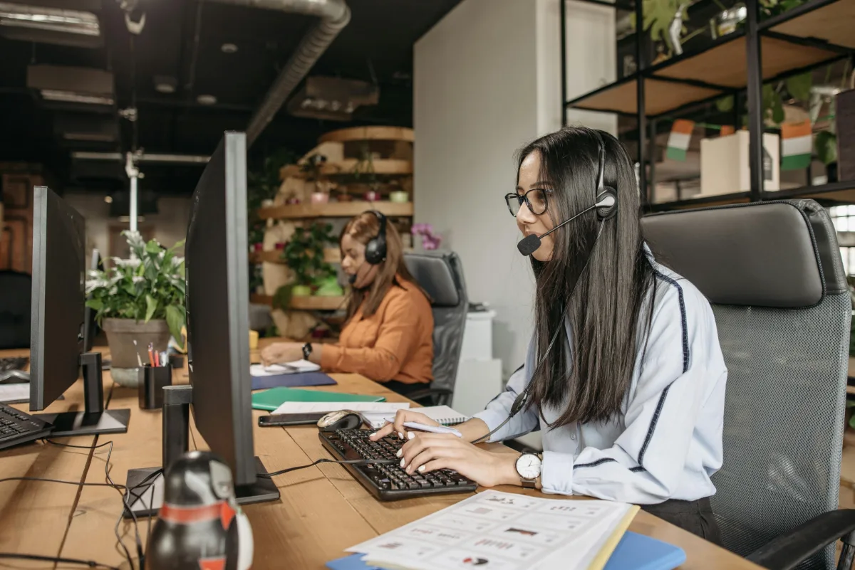 Customer service agents wearing headsets while working at computers in an office