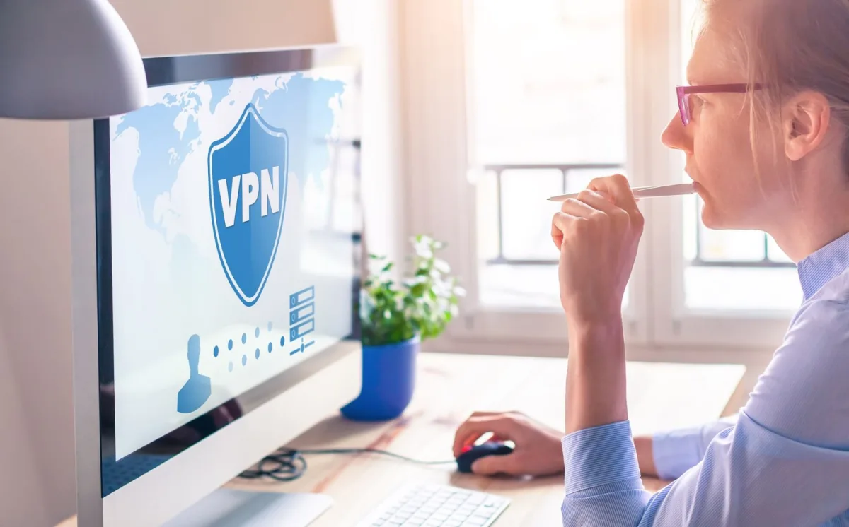 Man working at a desktop computer with a VPN shield symbol on the screen
