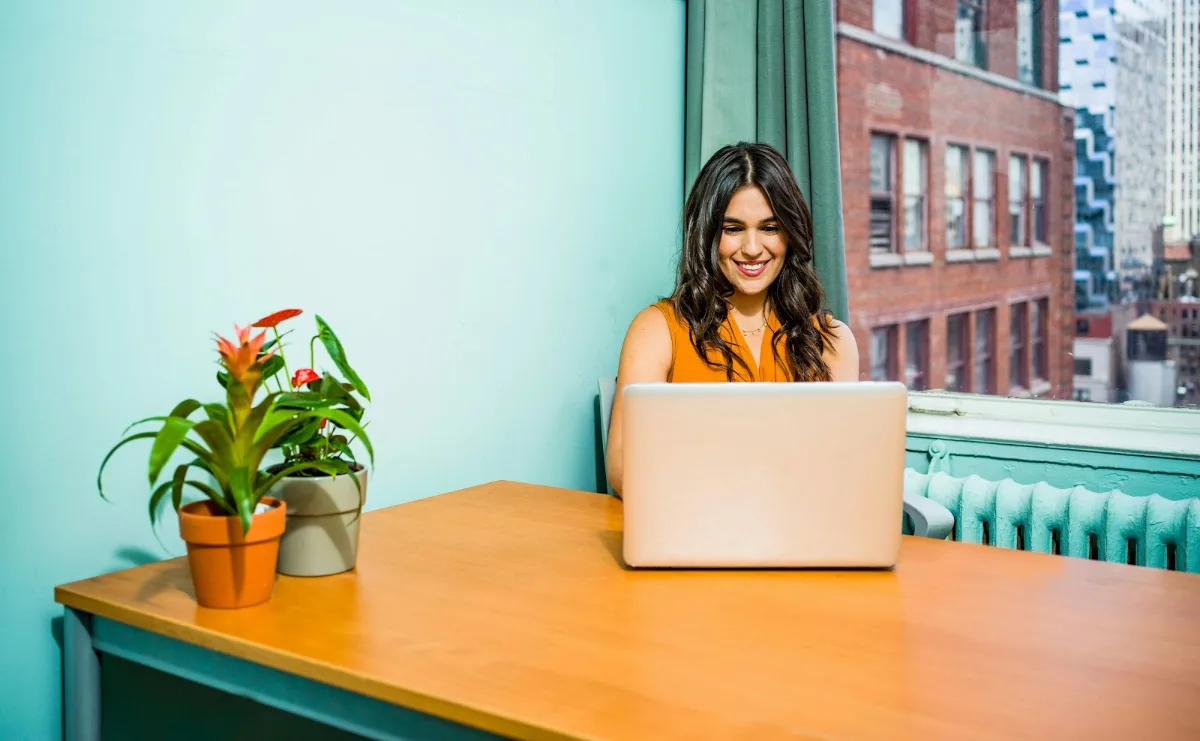 Woman using a laptop at a table in an apartment