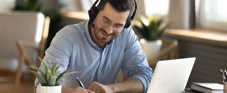 Smiling Caucasian man in headphones study on laptop